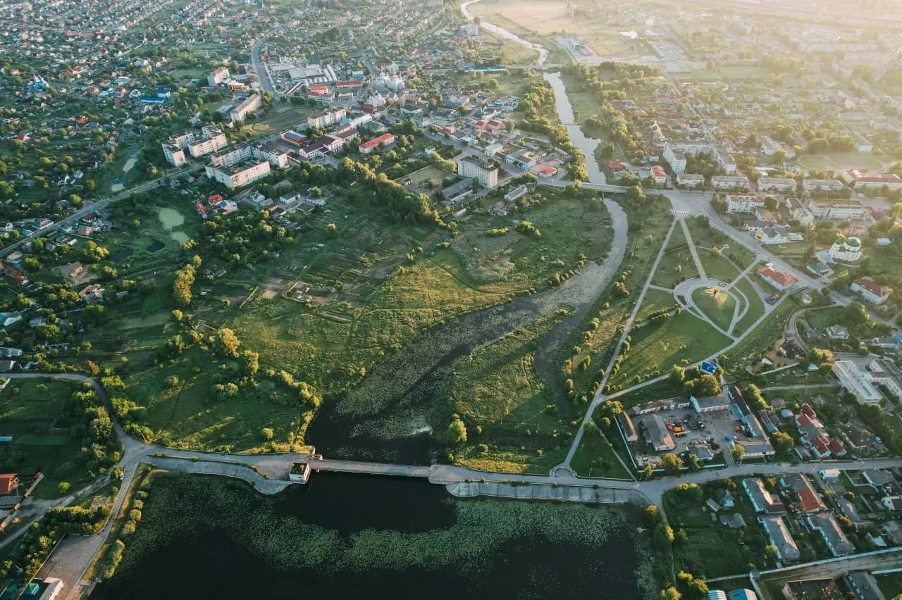Панорамный вид на Гродно с высоты, рекой Неман, мостом, зелёными берегами и исторической частью города.