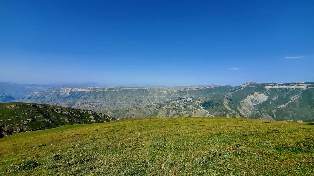 Горные пейзажи Дагестана с зелёными склонами, холмами и видом на кавказские долины.