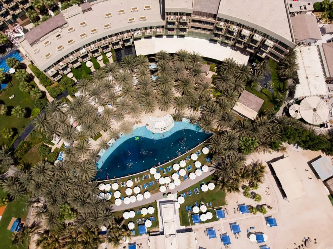 Rixos The Palm Dubai на Пальме Джумейра с бассейном, пальмами, частным пляжем и курортной территорией у моря.