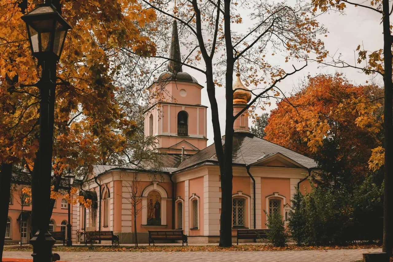 Православный храм в Беларуси осенью с тёплой листвой, старинной архитектурой и спокойной городской атмосферой.