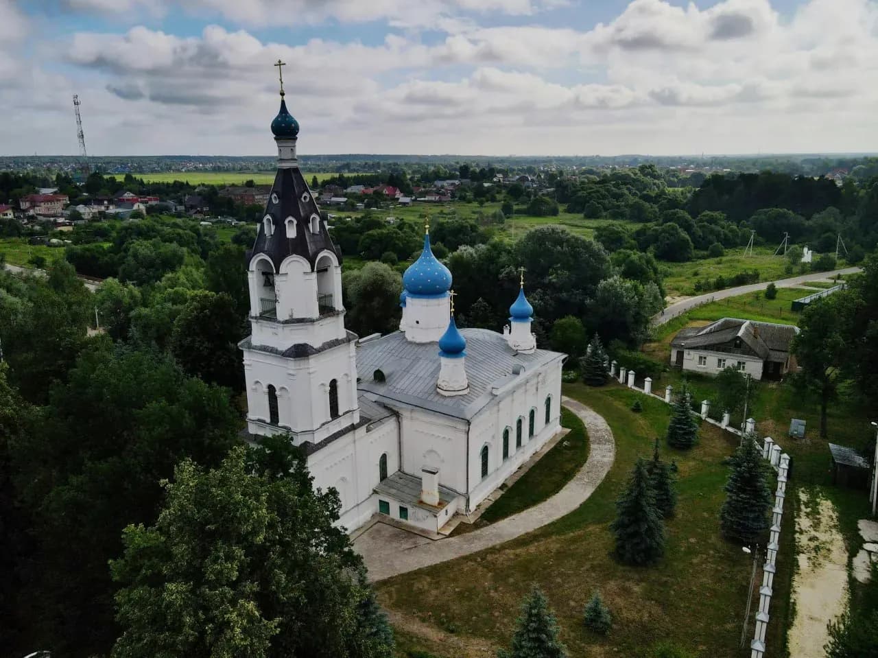 Православный храм в Гродно с голубыми куполами, белыми стенами и зелёной территорией.