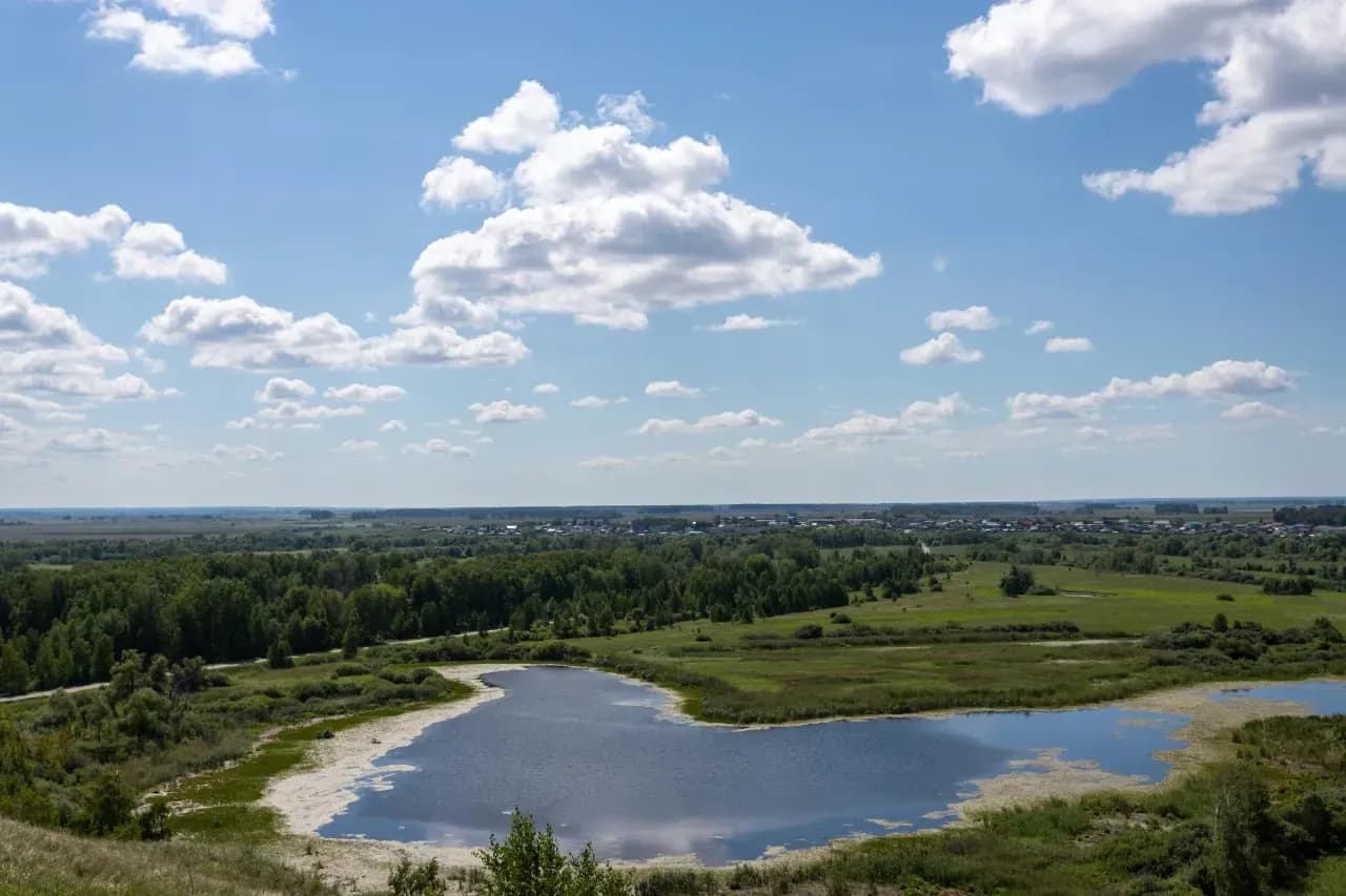 Озёрный край Беларуси с широким небом, лесами и спокойной гладью воды.