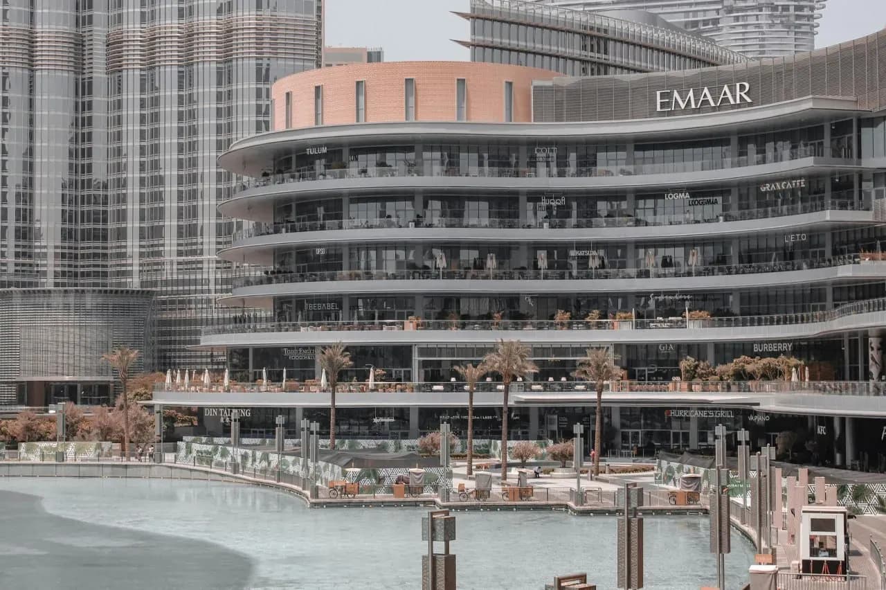 Фасад Dubai Mall в Даунтауне Дубая с террасами ресторанов, магазинами и городской архитектурой.