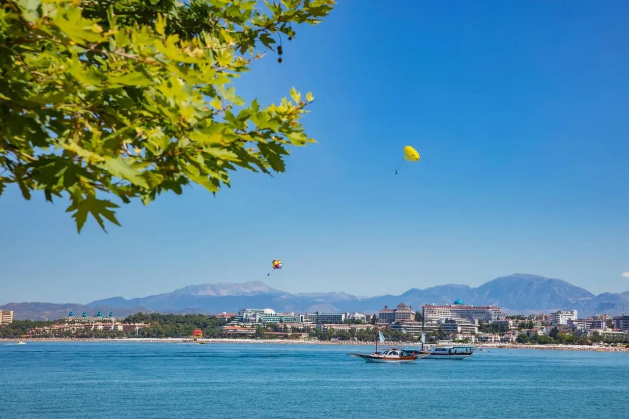 Панорамный вид на центр Кемера, море, горы, прогулочные катера и активный отдых на побережье.
