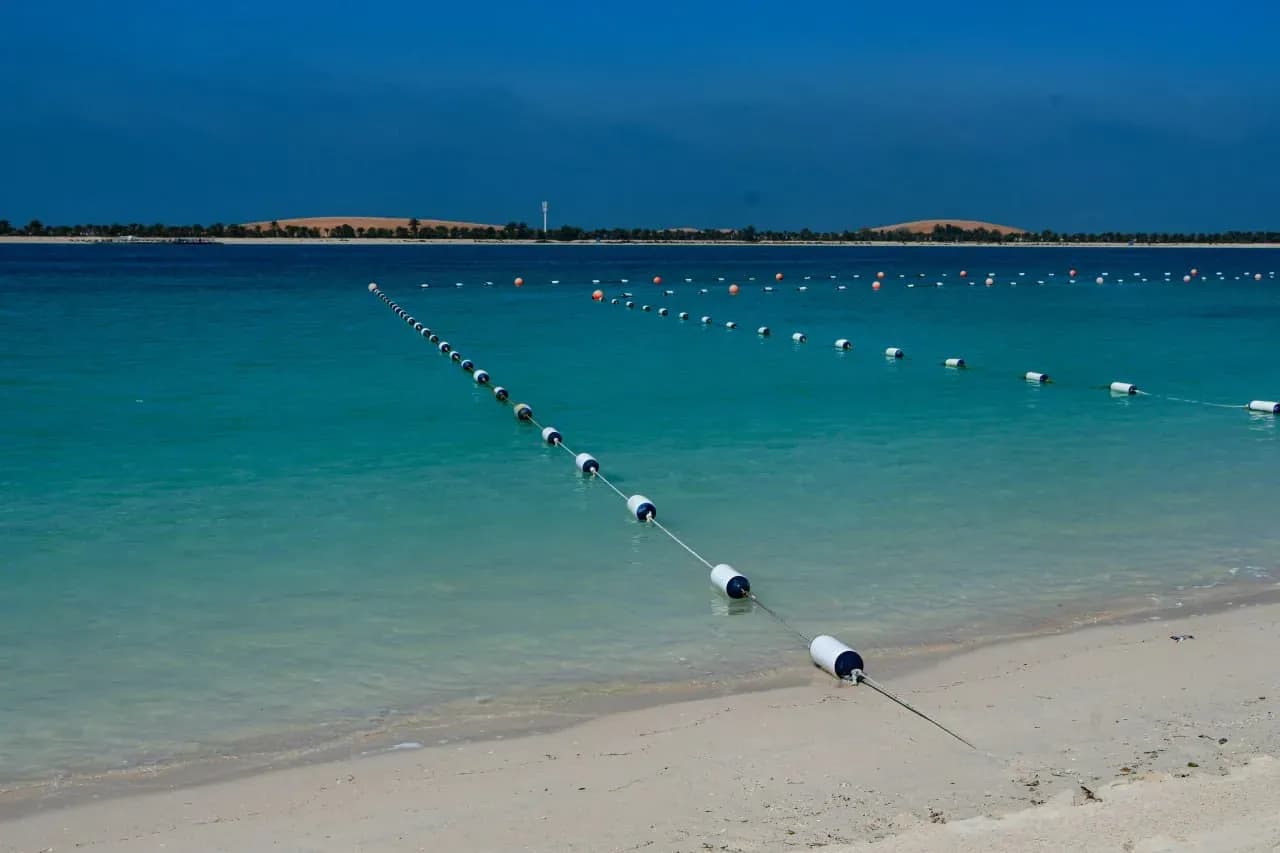 Yas Beach на острове Яс в Абу-Даби с белым песком, бирюзовой водой и спокойной пляжной линией.