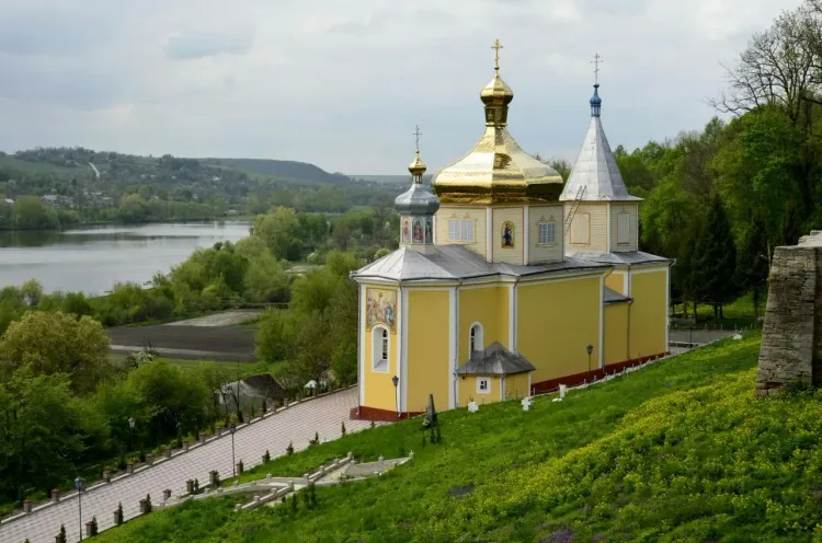 Храм в Гродно на высоком берегу Немана с жёлтым фасадом, куполами и видом на реку.