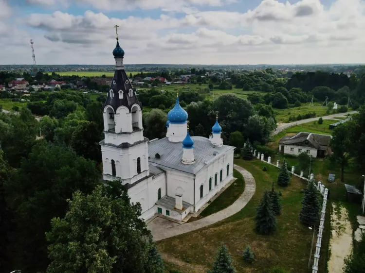 Православный храм в Гродно с голубыми куполами, белыми стенами и зелёной территорией.