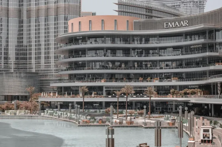 Фасад Dubai Mall в Даунтауне Дубая с террасами ресторанов, магазинами и городской архитектурой.