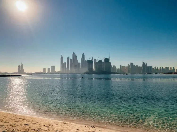 Пляж JBR в Дубае с видом на небоскрёбы, спокойную воду и городской курортный район.